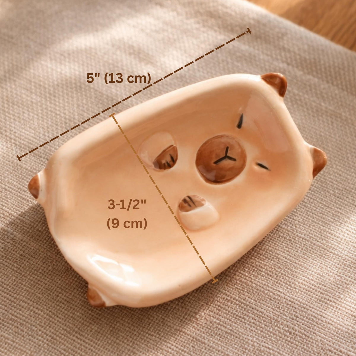 Ceramic capybara-shaped soap dish with measurements on a textured surface