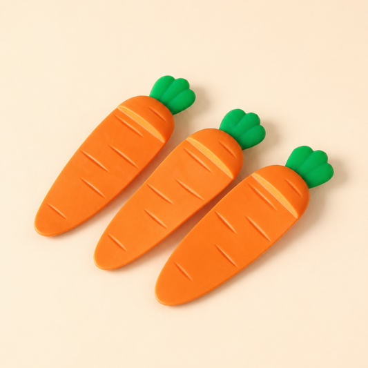 Three carrot-shaped carrot-shaped bookmarks with green tops on a wooden surface in orange and green, arranged diagonally on a solid beige background.