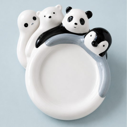 A white ceramic plate shaped like a ring, decorated with cartoon animal faces including a panda, penguin, bear, and seal, set against a light blue background.