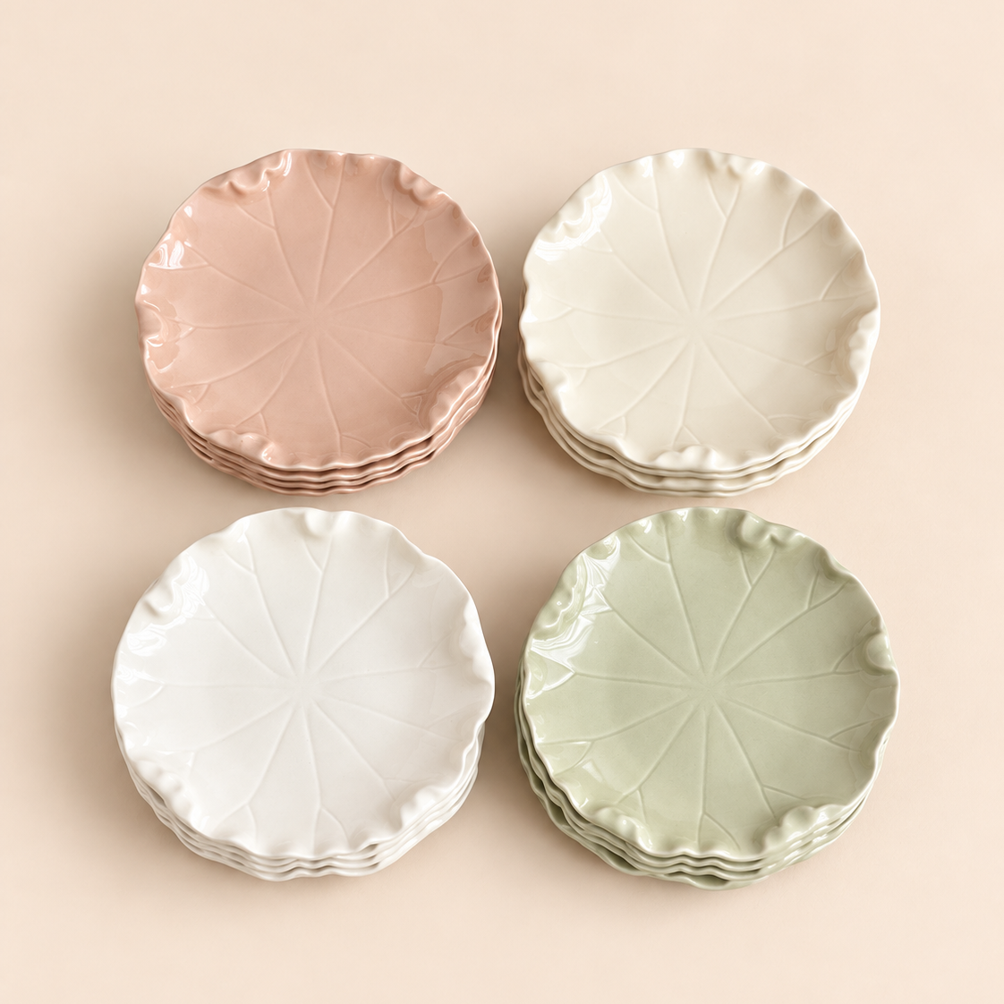 Four stacks of ceramic plates in dusty pink, off-white, white, and sage green, arranged in a 2x2 grid on a solid pale peach background. Each plate features a textured leaf vein pattern and a scalloped rim.
