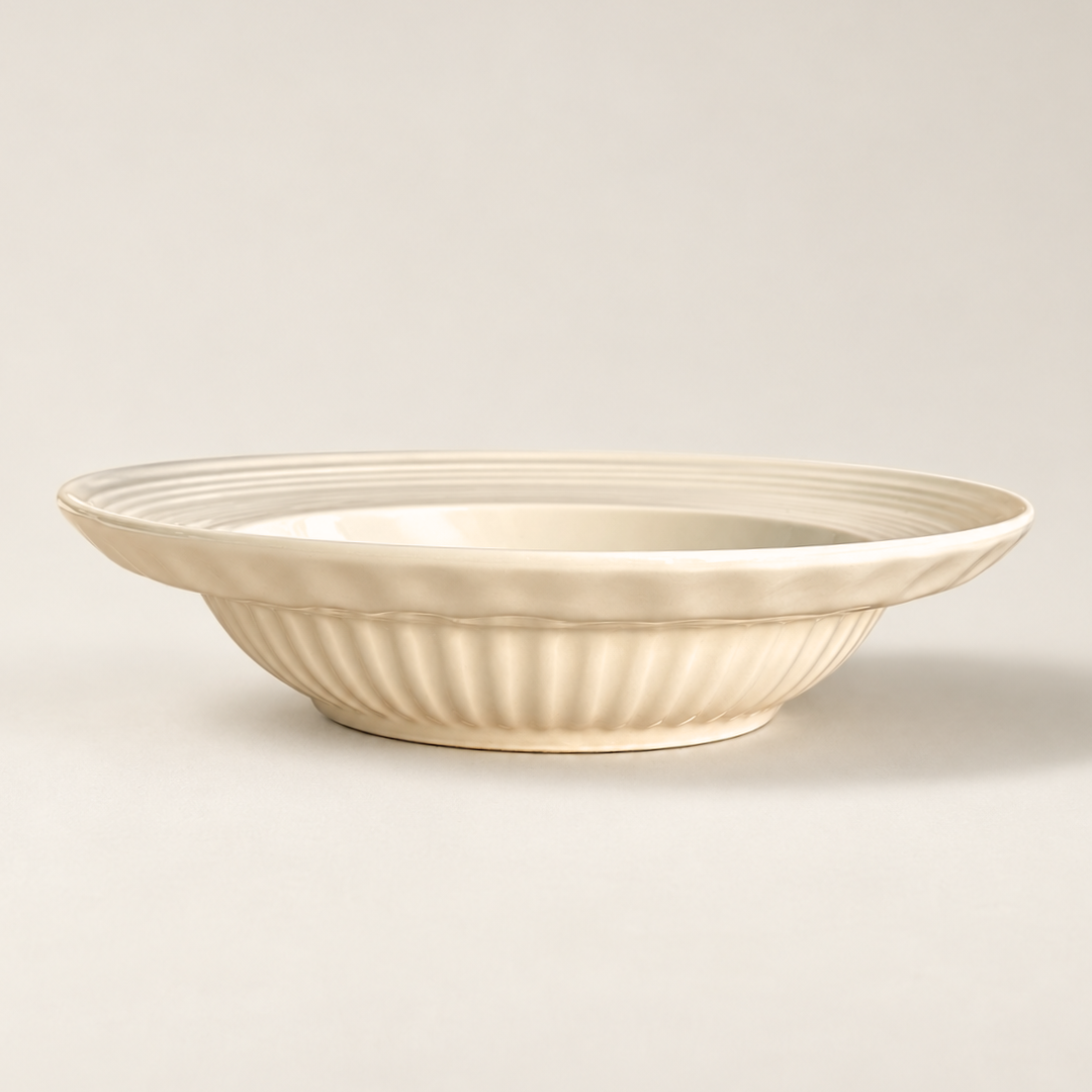 An off-white ceramic bowl with a fluted, ribbed exterior and a smooth, slightly tapered interior, shown on a neutral light beige background.